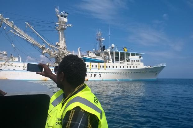 Fisheries officer in yellow on patrol vessel